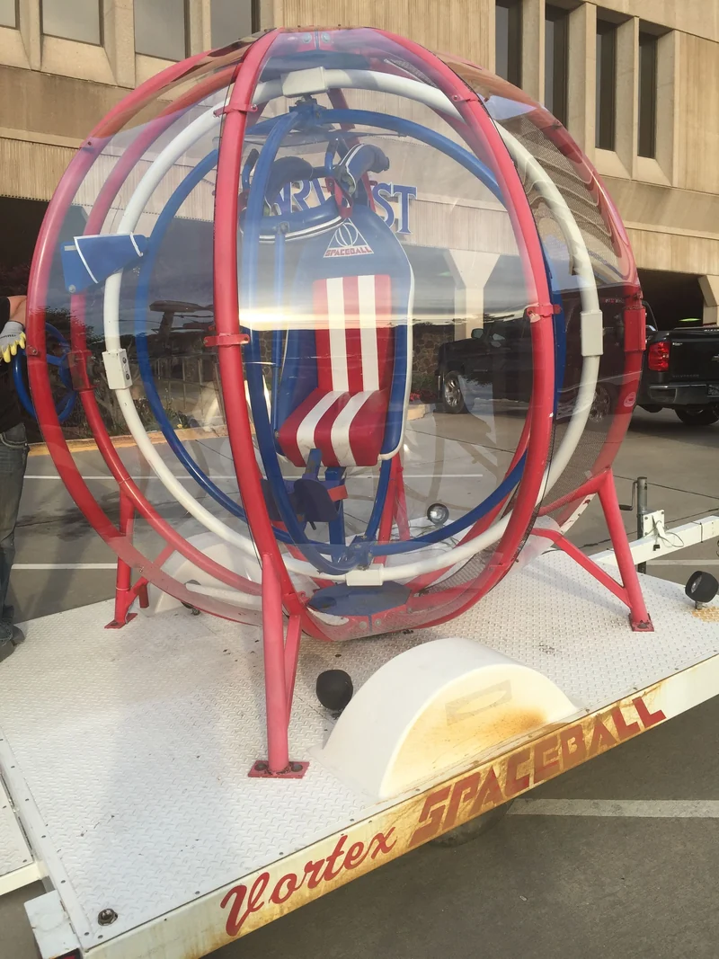 Red, white and blue Space Ball gyroscope with a blue seat on a trailer base; matching equipment model
