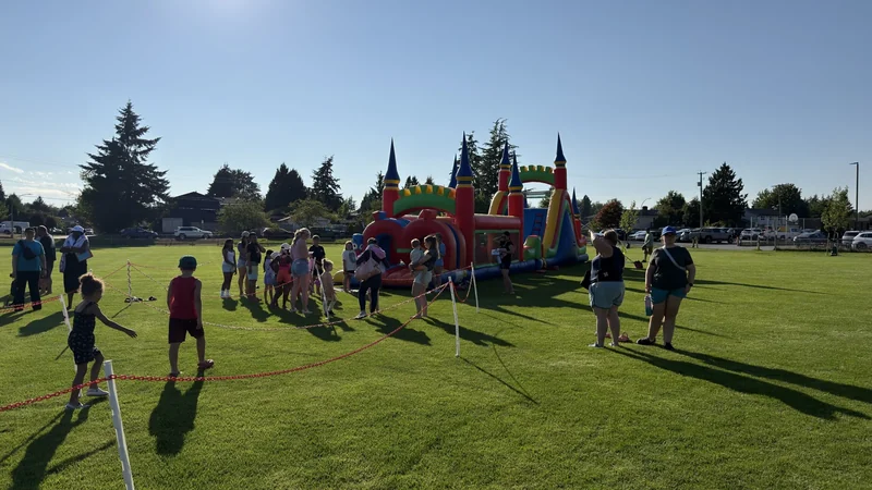 Guests and an inflatable activity with a defined waiting area on a grass field